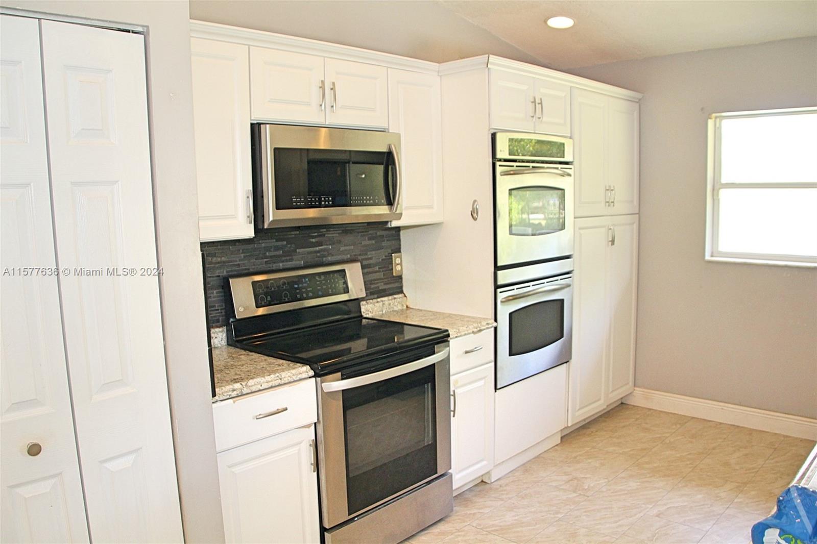 12646 55th Road North West Palm Beach, FL 33411 - Photo 4 of 10 a kitchen with white cabinets and stainless steel appliances