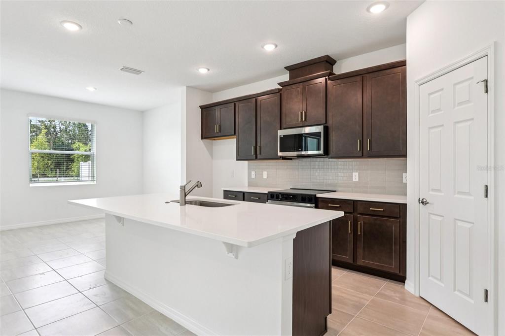 1756 Columbus Path St. Cloud, FL 34771 - Photo 4 of 37 a kitchen with kitchen island granite countertop a stove sink and microwave
