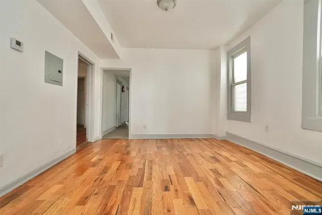 a view of an empty room with wooden floor and window