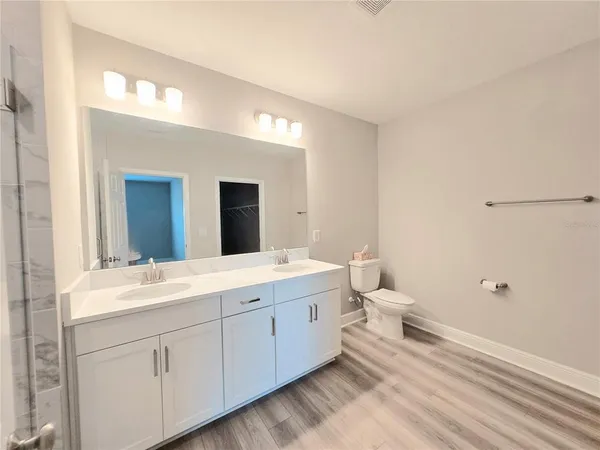 a spacious bathroom with a double vanity sink toilet and mirror