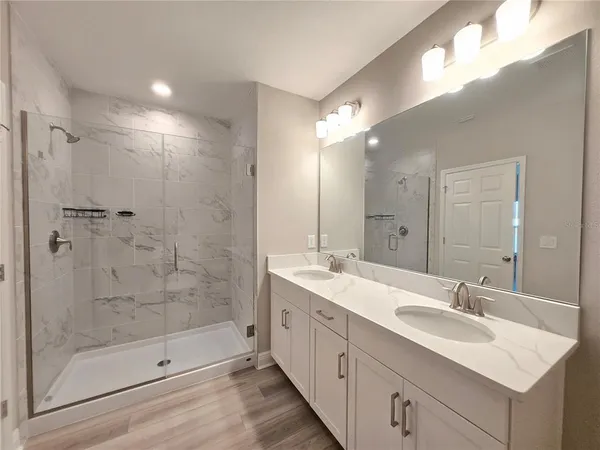 a bathroom with a double vanity sink mirror and shower