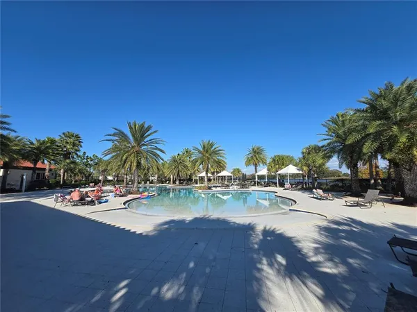 a view of swimming pool with outdoor seating and trees in the background