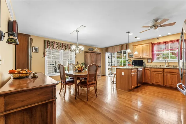 a kitchen with stainless steel appliances kitchen island granite countertop a stove a refrigerator a sink a dining table and chairs with wooden floor