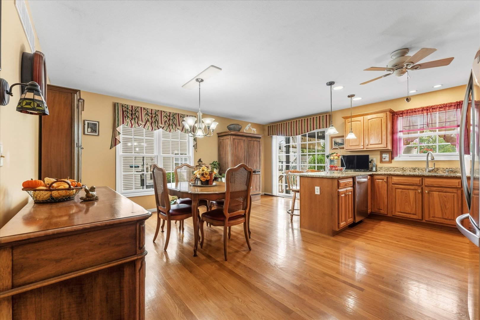 1706 Tin Cup Road, Unit 1706 Mahomet, IL 61853 - Photo 11 of 43 a kitchen with stainless steel appliances kitchen island granite countertop a stove a refrigerator a sink a dining table and chairs with wooden floor