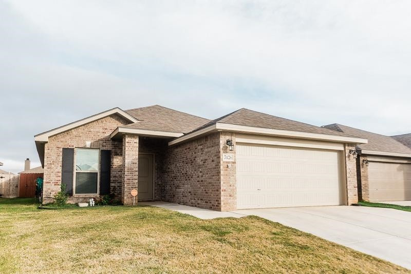 7426 103rd Street Lubbock, TX 79424 - Photo 2 of 10 a front view of a house with a yard and garage