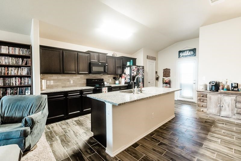 7426 103rd Street Lubbock, TX 79424 - Photo 8 of 10 a kitchen with stainless steel appliances granite countertop a stove top oven a sink a dining table and chairs with wooden floor