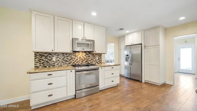 a kitchen with granite countertop a refrigerator sink and cabinets
