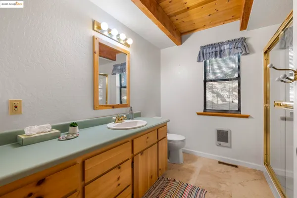 a bathroom with a sink a mirror a toilet and a window
