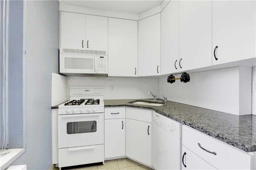 9902 3rd Avenue, Unit 1M Brooklyn, NY 11209 - Photo 11 of 20 a kitchen with granite countertop white cabinets and white appliances