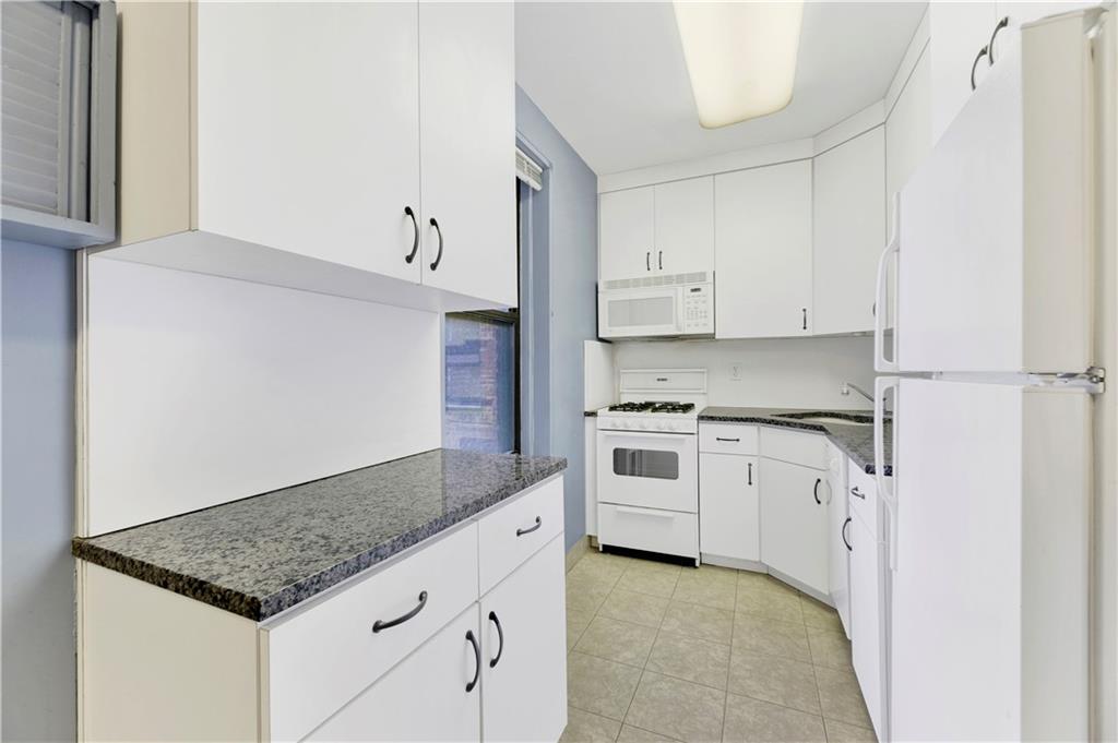 9902 3rd Avenue, Unit 1M Brooklyn, NY 11209 - Photo 13 of 20 a kitchen with granite countertop white cabinets and white appliances