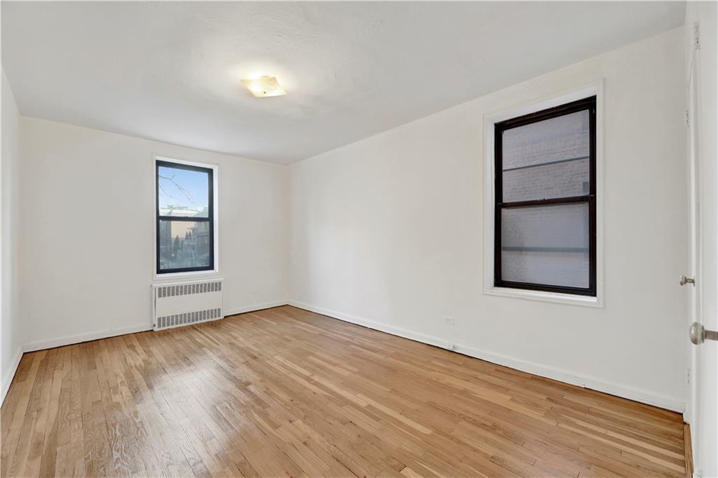 9902 3rd Avenue, Unit 1M Brooklyn, NY 11209 - Photo 6 of 20 an empty room with wooden floor and windows