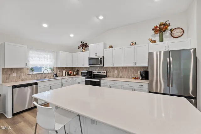a kitchen with granite countertop a refrigerator stove and white cabinets