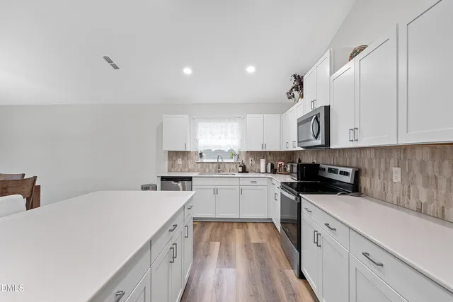 a kitchen with a sink a stove top oven and white cabinets