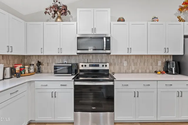 a kitchen with white cabinets and a stove with a sink