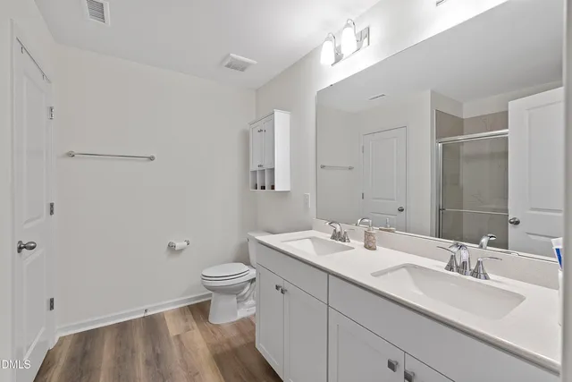 a bathroom with a double vanity sink toilet and a mirror