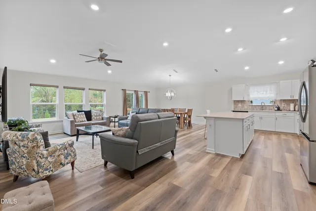 a living room with couches and kitchen view with wooden floor