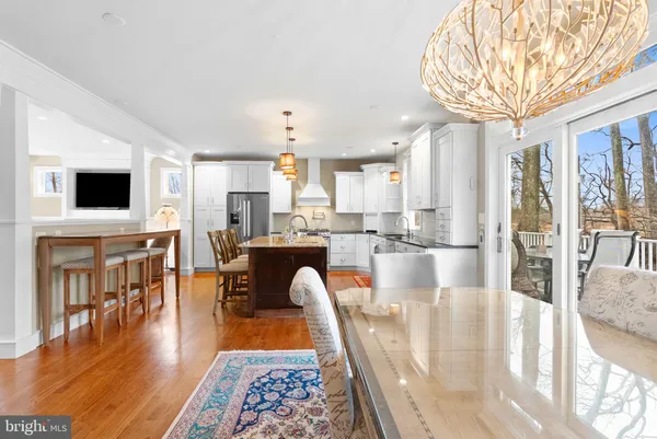 a kitchen with stainless steel appliances granite countertop a dining table chairs and a living room view