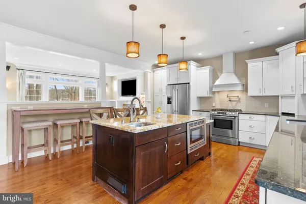 a kitchen with stainless steel appliances granite countertop a stove a sink dishwasher and a dining table with cabinets