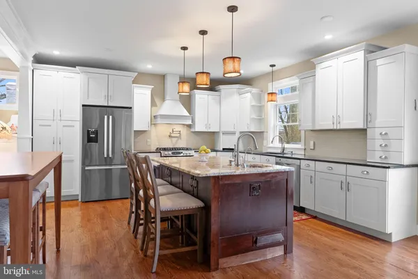 a kitchen with stainless steel appliances granite countertop a sink a stove a refrigerator and island with wooden floor