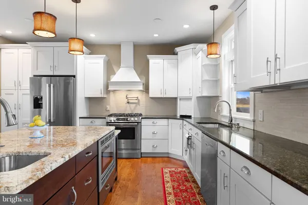 a kitchen with stainless steel appliances granite countertop a sink a stove and a refrigerator