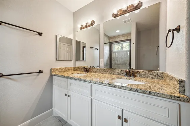 a bathroom with a granite countertop sink and a mirror