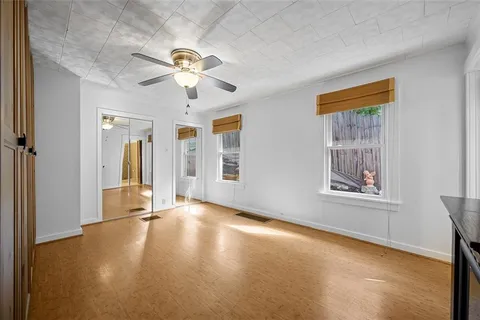 a view of an empty room with window and chandelier fan