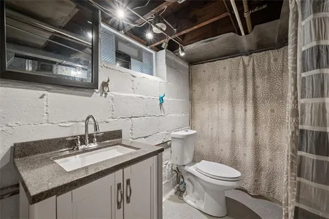 a bathroom with a granite countertop sink a toilet and a mirror