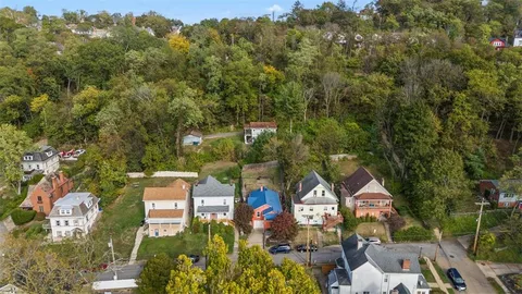 an aerial view of residential houses with outdoor space and trees