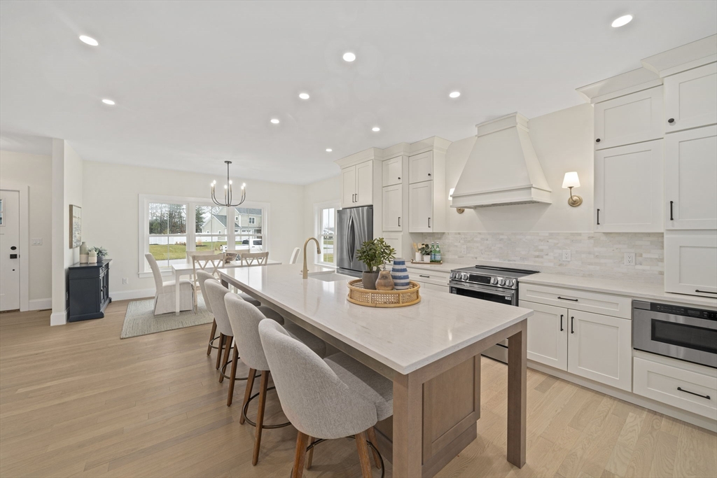 45 Red Gold Farm Road Marshfield, MA 02050 - Photo 3 of 40 a kitchen with a sink a stove a kitchen island and chairs with wooden floor