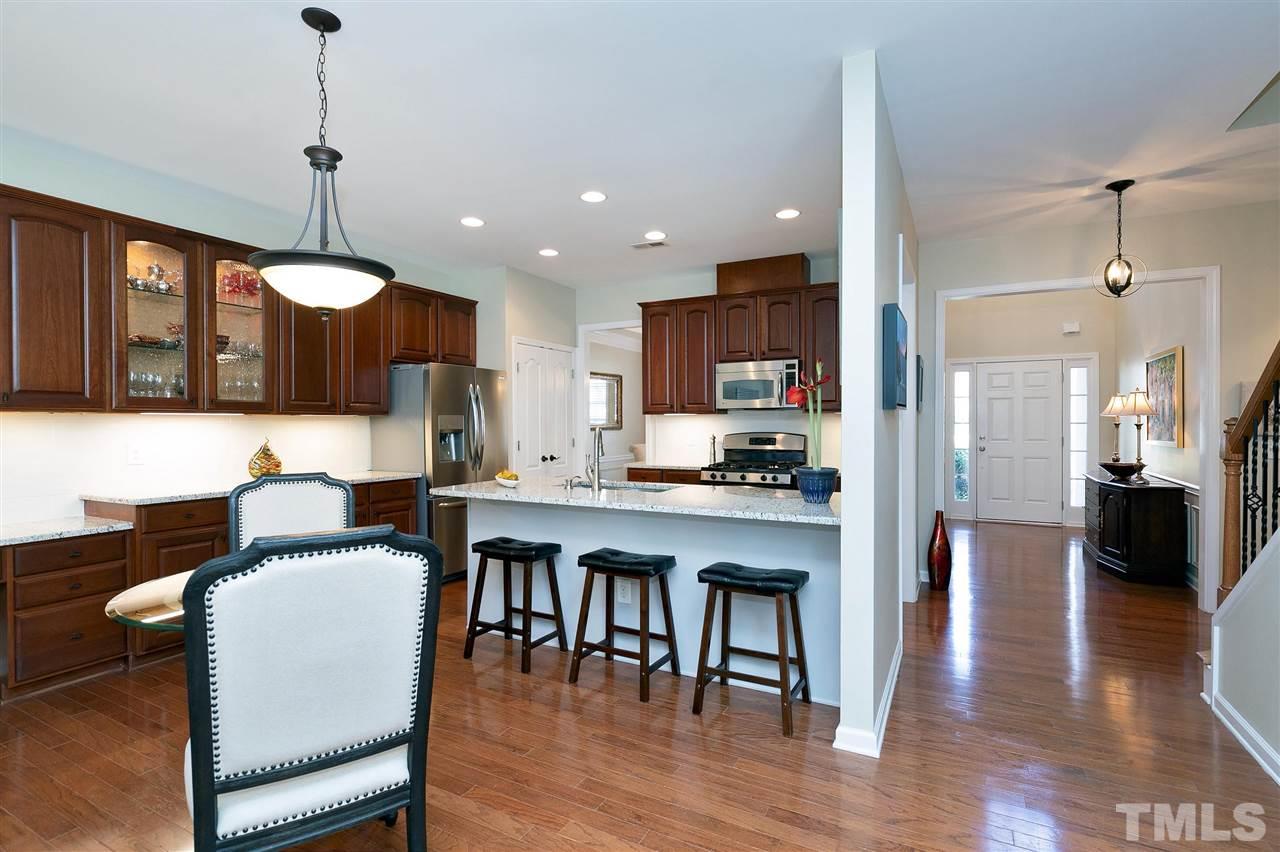 5110 Kate Denson Way Raleigh, NC 27612 - Photo 8 of 30 a open kitchen with stainless steel appliances granite countertop a stove a refrigerator a kitchen island a dining table and chairs with wooden floor
