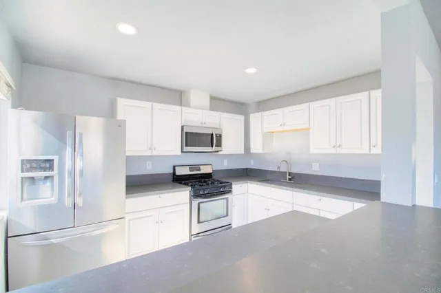 a kitchen with stainless steel appliances granite countertop a stove a sink and a refrigerator