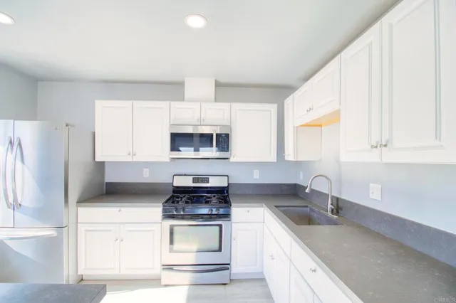 a kitchen with white cabinets stainless steel appliances and sink