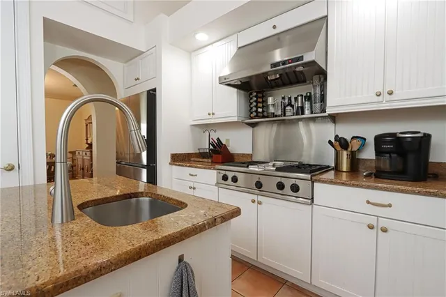 a kitchen with granite countertop a sink a stove and cabinets