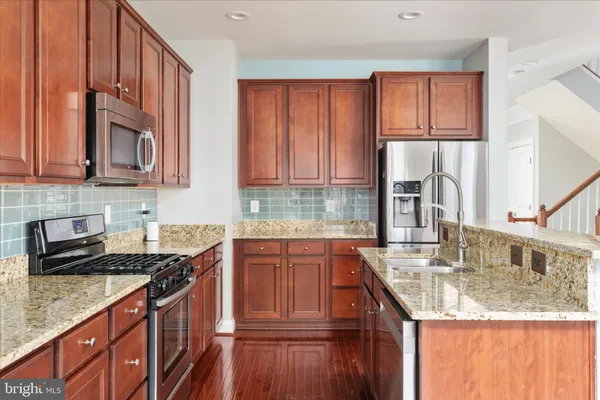 a kitchen with stainless steel appliances granite countertop a sink stove and cabinets