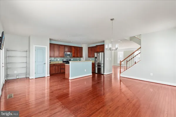 a view of a kitchen and an empty room with wooden floor