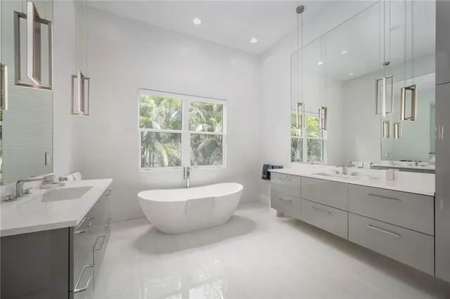 a bathroom with a double vanity sink bathtub and window
