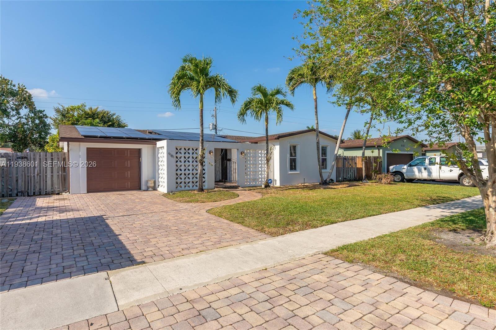 9181 Southwest 55th Street Cooper City, FL 33328 - Photo 2 of 7 a front view of a house with a garden and trees
