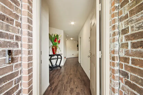 a view of a hallway with wooden floor and a bathroom
