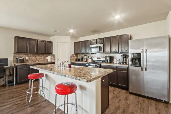a kitchen with stainless steel appliances granite countertop a refrigerator stove top oven and sink