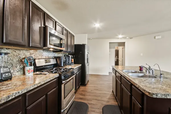 a kitchen with stainless steel appliances granite countertop a sink stove and refrigerator