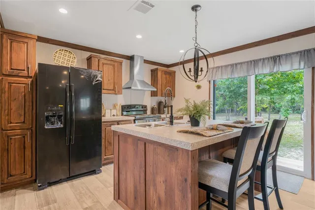 a kitchen with stainless steel appliances granite countertop a refrigerator a sink dishwasher a dining table and chairs with wooden floor