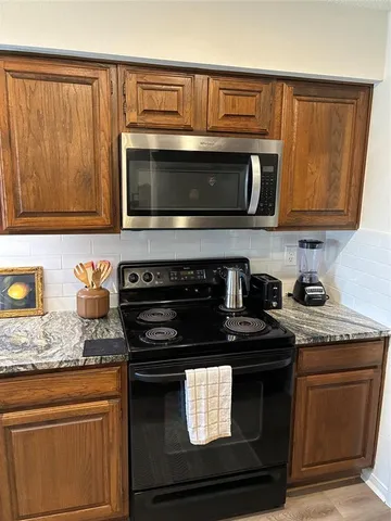 a kitchen with granite countertop cabinets stove top oven and microwave