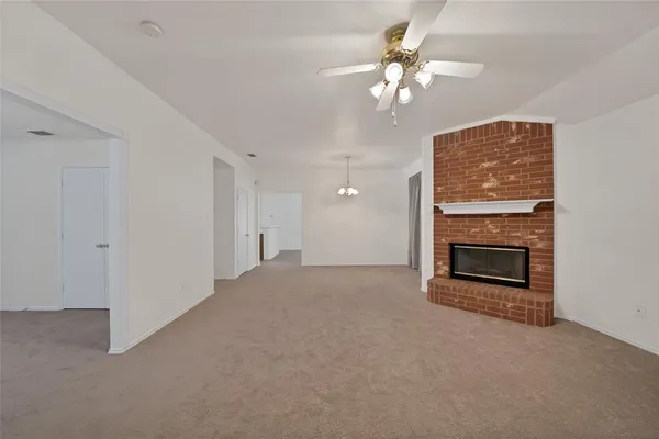 a view of a livingroom with a fireplace a ceiling fan and a fireplace