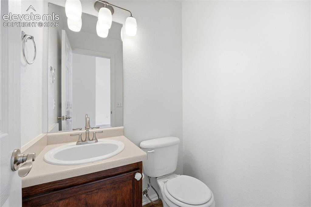 7904 Coffee Road Peyton, CO 80831 - Photo 17 of 48 Powder room featuring a dark wood vanity with white ceramic sink, light-toned countertop, and brushed nickel faucet