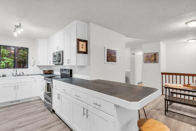 1539 East 450 South Springville, UT 84663 - Photo 11 of 49 Kitchen featuring white shaker cabinetry, stainless steel appliances, dark countertops, and wood-finish flooring