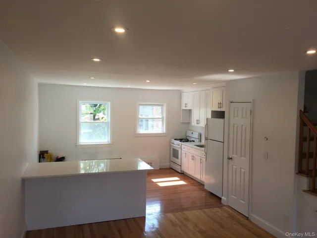 a kitchen with stainless steel appliances granite countertop a refrigerator a sink dishwasher a stove and white countertops with wooden floor