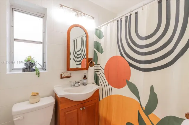 a bathroom with a sink a mirror a toilet and a window