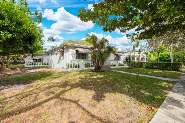 a view of an house with backyard and trees