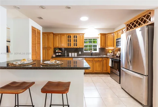 a kitchen with stainless steel appliances granite countertop a stove a sink a refrigerator and island