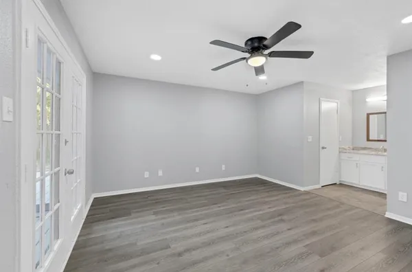 an empty room with wooden floor and a ceiling fan